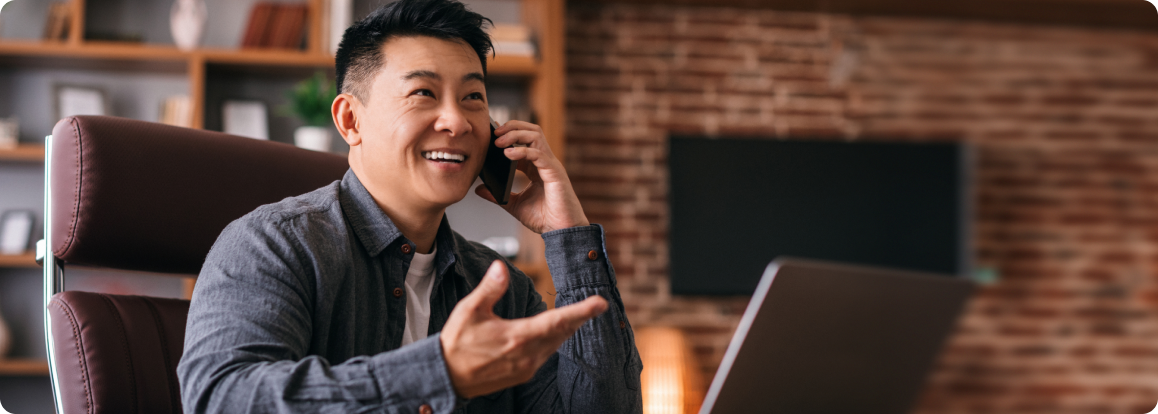 Man smiling while talking on the phone in a modern office setting, representing D&L Transport’s commitment to supporting agents' success and well-being through their Better Life program